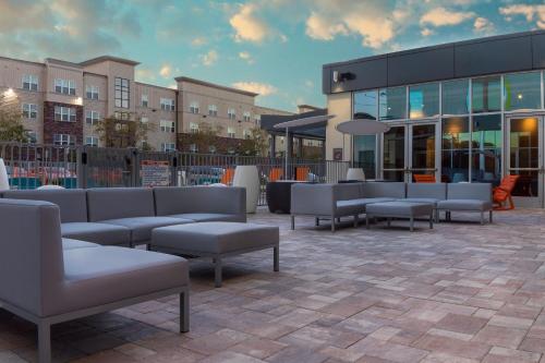 a patio with couches and tables in front of a building at Aloft Gainesville University Area in Gainesville