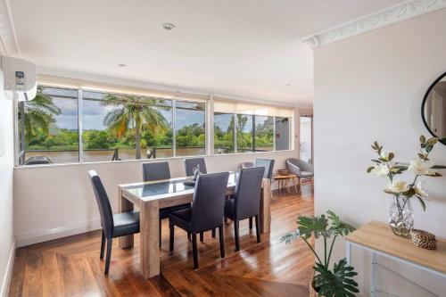 a dining room with a table and chairs and windows at Clarence River Retreat - Oceanstays - Farmstay & Jetty in Lawrence