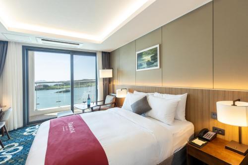 a hotel room with a large bed and a window at Ramada Plaza by Wyndham Dolsan Yeosu in Yeosu