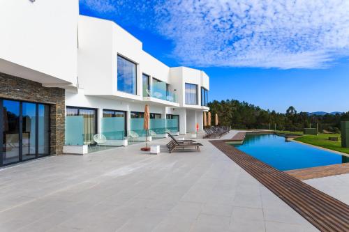 a villa with a swimming pool and a patio at Enigma - Nature & Water Hotel in São Teotónio