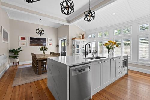 a kitchen with white cabinets and a dining room with a table at Luxury Villa on Napier Hill in Napier