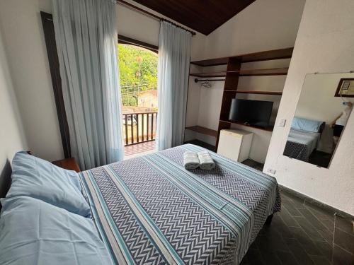 a bedroom with a bed and a large window at Pousada Recanto do Patrimônio in Paraty
