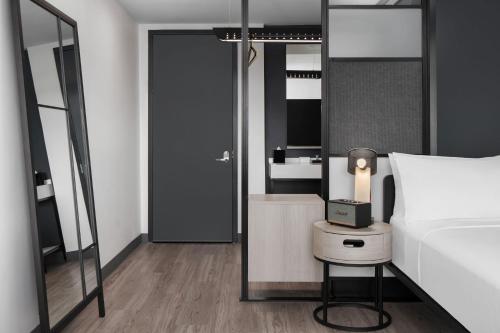 a bedroom with a bed and a table with a lamp at Aloft Houston Shenandoah - The Woodlands in Shenandoah