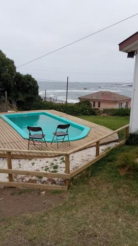 a swimming pool with two chairs on a wooden deck at MarAzul in Valparaíso