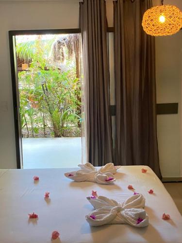 a white bed with flowers on it with a window at Pousada Águas de Tamandaré in Tamandaré