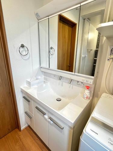 a white bathroom with a sink and a mirror at Casa Stella 5 by Liaison in Osaka