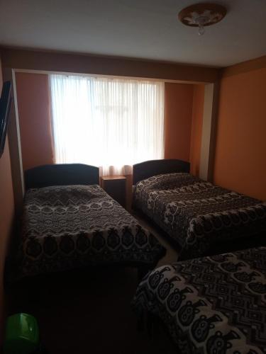 two beds in a room with a window at Hostal Puerto Alegre in Copacabana