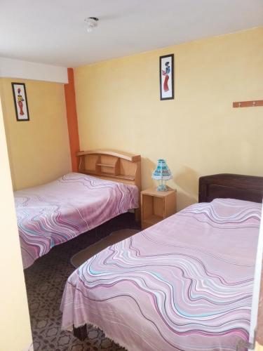 two beds in a room with pink and purple sheets at Hostal Puerto Alegre in Copacabana