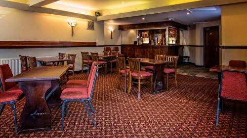 a restaurant with wooden tables and red chairs at The Miners Arms in Leeds