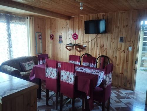 a dining room with a table and chairs and a tv at Cabañas encanto de Chovellen in Pelluhue