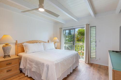 a white bedroom with a bed and a window at Puamana 26B in Princeville