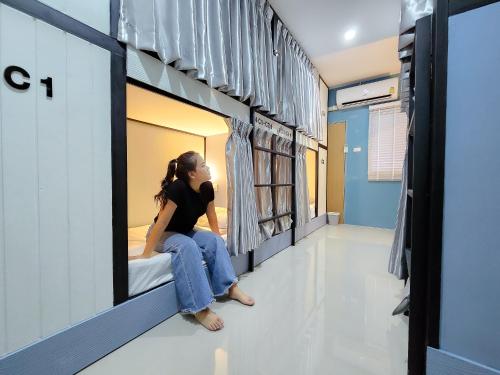 a woman sitting on a bed in a hospital room at Bunk Ubon Hostel in Ban Na Khwai