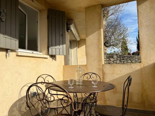 une table et des chaises sur une terrasse avec une fenêtre dans l'établissement Maison sur la colline du Barroux, à Le Barroux