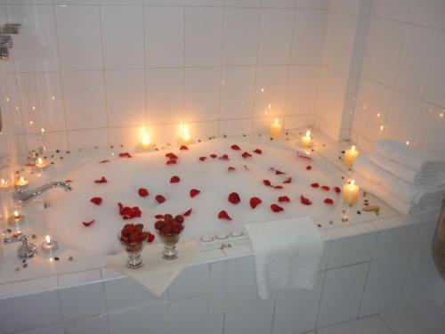 Hotel La Joya في هواراس: حوض استحمام مليء بالشموع والورود الحمراء