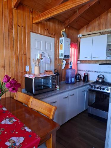 a kitchen with wooden walls and a table and a microwave at Cabaña Mi Paraíso in Valparaíso