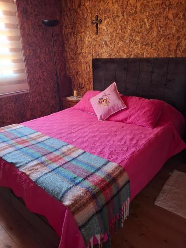 a bedroom with a pink bed with a pink pillow at Cabaña Mi Paraíso in Valparaíso