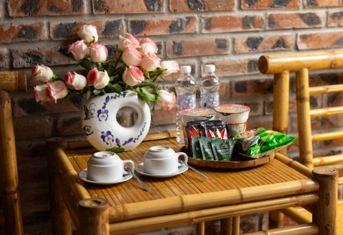 a table with a vase of flowers and teaisers at Tam Coc Moonlight Sweet Home in Ninh Binh