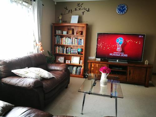 a living room with a couch and a flat screen tv at Monique's Queen Rm AirCon TV in Auckland
