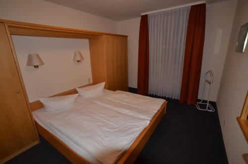 um quarto com uma cama com lençóis brancos e almofadas em Ferienwohnung 2 im Haus Hühnergott Sellin em Ostseebad Sellin