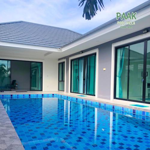 a swimming pool in front of a house at PAAK Pool Villa Cha-am in Cha Am