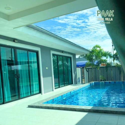 a swimming pool in front of a house at PAAK Pool Villa Cha-am in Cha Am