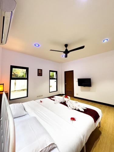 a bedroom with a large bed with a ceiling fan at villa kitty in Ban Thung Satong
