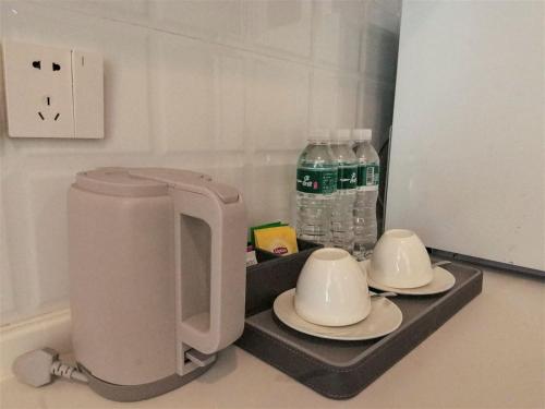 a coffee maker and two cups and water bottles at 浮生慢遇酒店 in Dali Airport