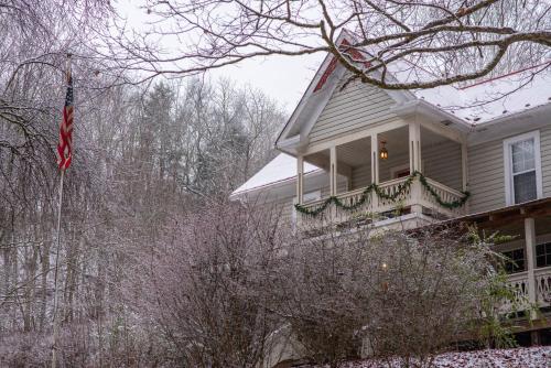 a house with a porch and a flag on it at Moore House Inn & Cabins in Marlinton