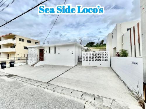 a large white building with a white fence at Sea Side Loco's in Yaka