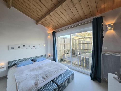 una camera da letto con un letto e una grande finestra di Maison en bois avec piscine privée chauffée, terrasse et jardin - Ideal famille et nature - FR-1-616-96 a Montagrier