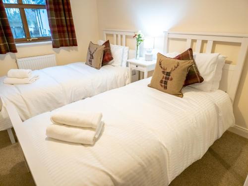 two beds in a room with towels on them at Lairig Ghru Lodge in Aviemore