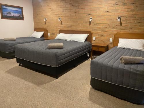 a room with two beds and a brick wall at Quays Motel San Remo in San Remo