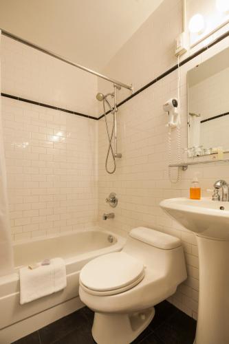 a white bathroom with a toilet and a sink at Hotel Chateau de l'Argoat in Montréal