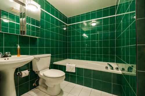 a green tiled bathroom with a toilet and a sink at Hotel Chateau de l'Argoat in Montréal