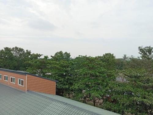 a roof of a house with trees in the background at Hakka Eco-farm 雅歌園民宿食農教育有機農場 in Wanluan