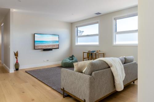 a living room with a couch and a flat screen tv at Rosewood Retreat New luxury Home in Rosebud