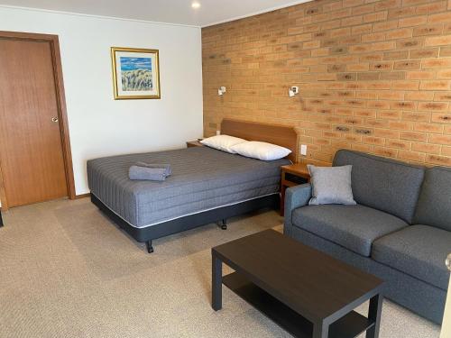 a small room with a bed and a couch at Quays Motel San Remo in San Remo