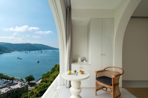 a room with a table and a view of the water at Miyue Shenzhen Blue and White Holy Island Cliff Pool Hotel in Shenzhen