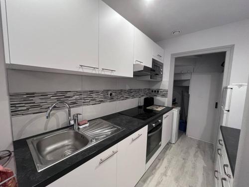 une cuisine avec un évier en acier inoxydable et des armoires blanches dans l'établissement Appartement duplex à Cauterets avec sauna privé et wifi - FR-1-812-87, à Cauterets