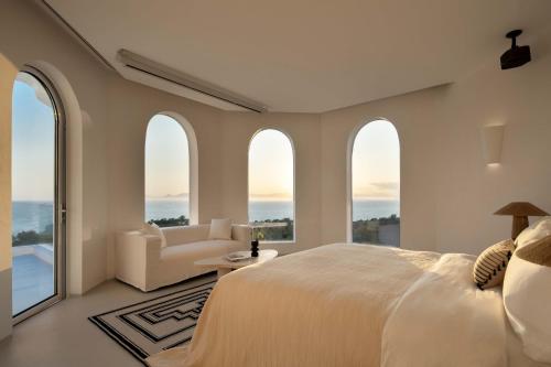 a bedroom with arched windows and a bed and a couch at Miyue Shenzhen Blue and White Holy Island Cliff Pool Hotel in Shenzhen