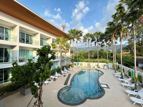 a resort with a pool and chairs and palm trees at Clear House Resort - SHA Extra Plus in Kamala Beach