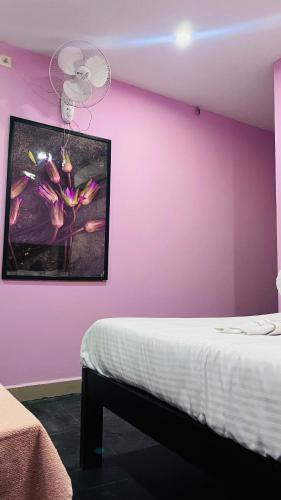 a bedroom with a pink wall with a bed and a painting at skywayrooms near Indira Gandhi signal in Puducherry