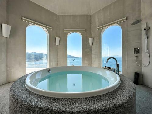 a large bathroom with a large tub with windows at Miyue Shenzhen Blue and White Holy Island Cliff Pool Hotel in Shenzhen