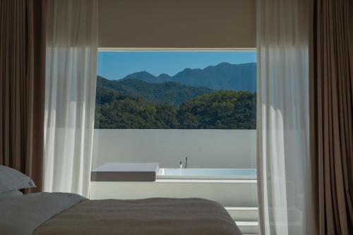a bedroom with a large window with a mountain view at Miyue Shenzhen Blue and White Holy Island Cliff Pool Hotel in Shenzhen