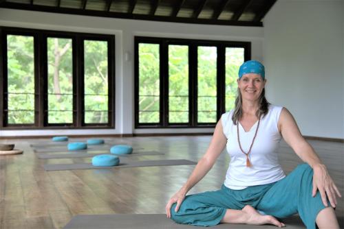 a woman sitting on a yoga mat in a room at Niyagama House in Galle