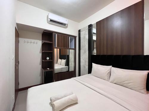 PampangにあるWarm and Cozy 2BR Vida View Makassar Apartment By Travelioのベッドルーム(白いベッド、黒いヘッドボード付)