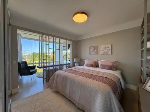 a bedroom with a bed and a large window at Casa Luxuosa no Condomínio Condado de Capão in Capão da Canoa