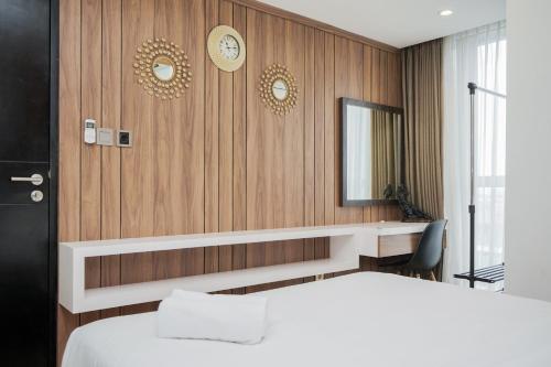 a bedroom with a bed and a desk and a mirror at Stunning and Spacious 1BR at Branz BSD City Apartment By Travelio in Tangerang