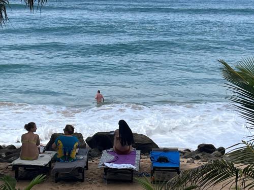 a group of people sitting on chairs on the beach at Blue Wave Beach Villa by Aaryan Group in Ambalangoda