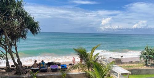 a group of people sitting on a beach near the ocean at Blue Wave Beach Villa by Aaryan Group in Ambalangoda